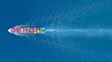 Aerial top view cargo maritime ship with contrail ocean ship carrying container running export concept technology freight shipping sea freight by express ship lr
